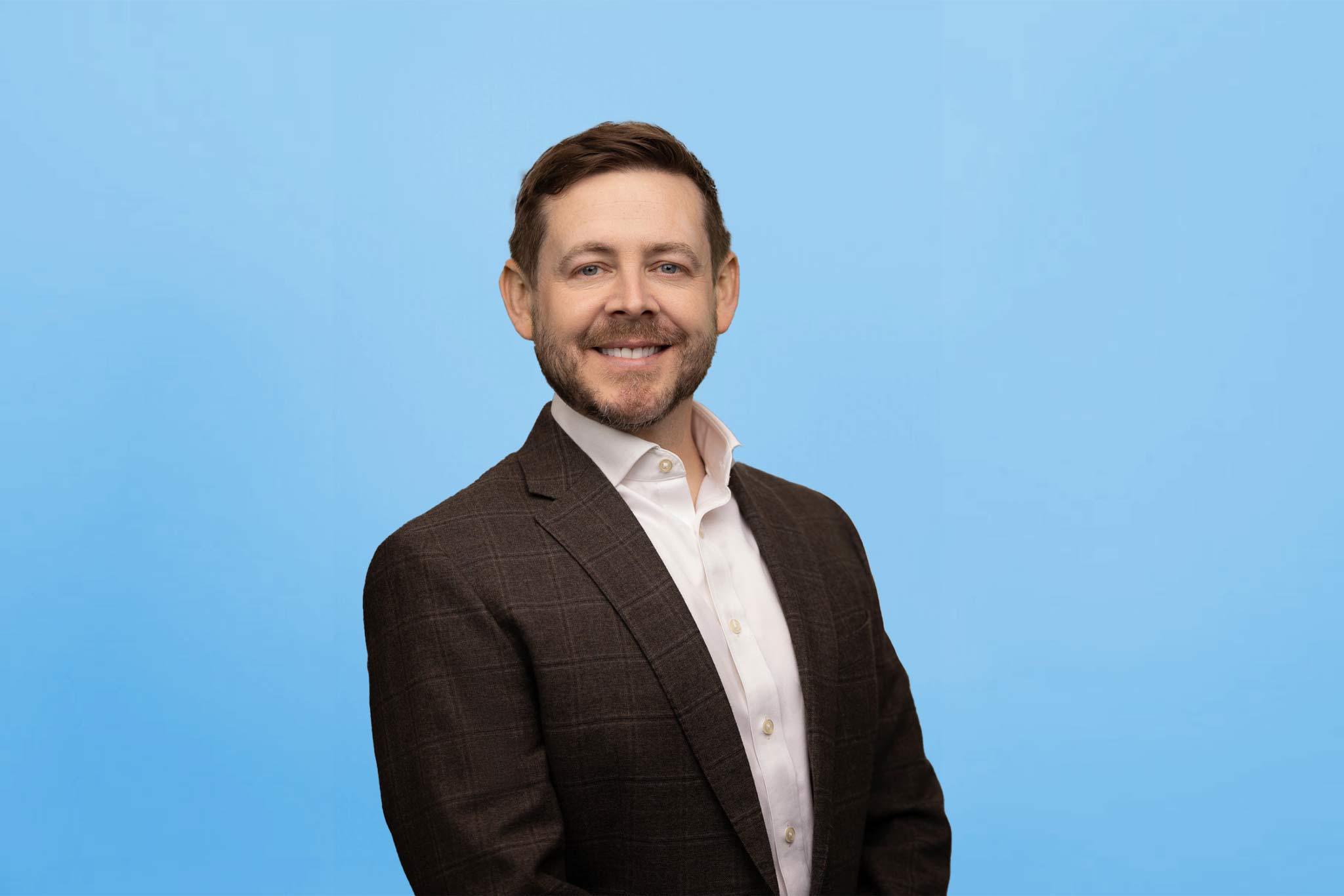 Professional headshot of Dr. Kevin Burgdorf against a blue background, highlighting his friendly and approachable demeanor.