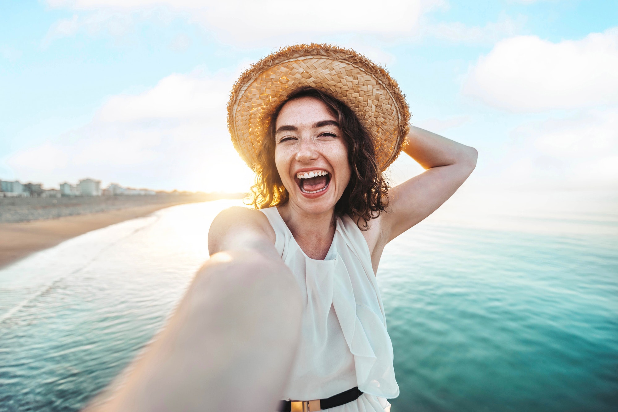 Happy woman taking a selfie on the beach, representing the joy and confidence of patients treated by Dr. Kevin Burgdorf.