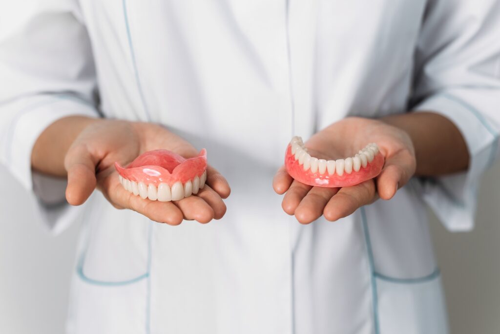 Close-up of a dentist holding dentures in both hands, representing Dr. Kevin Burgdorf, DDS in St. Charles, MO, providing personalized denture solutions to restore smiles and enhance quality of life.