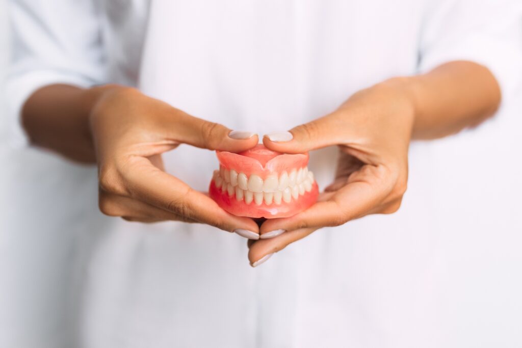 Close-up of a dentist holding natural-looking dentures, representing modern custom dental prosthetics available at Dr. Kevin Burgdorf’s St. Charles office